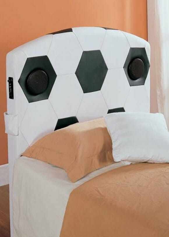 Uma cama com cabeceira que imita bola de futebol e com speakers embutidos.