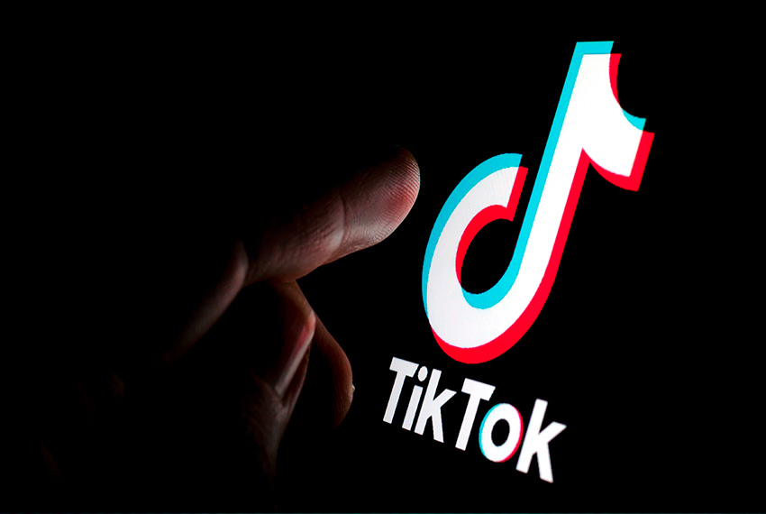 Homem apontando dedo na tela do celular com logo do TikTok
